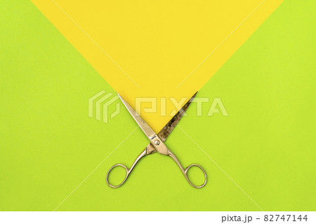 Colorful green and yellow background with metal scissors Colorful green and yellow background with metal scissors 82747144