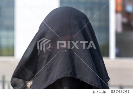 Portrait of a Muslim woman in national clothes covering her face in a European city Portrait of a Muslim woman in national clothes covering her face in a European city 82748241