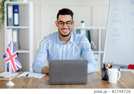 Cheerful male tutor having video call with students on laptop, giving English lesson on web from home 82748726