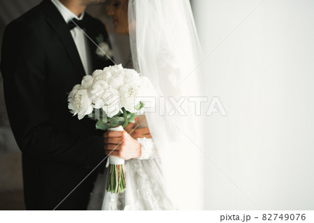 Beautiful young wedding couple posing with bouquet of flowers in hands 82749076