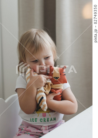Little baby girl playing with funny small tiger toy, symbol of new 2022 in a sunny nursery 82749350