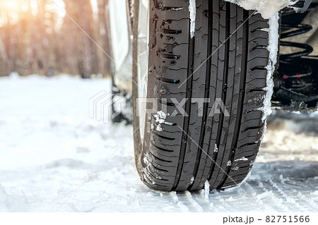 Close-up detail view of car wheel with unsafe summer tread tire during driving through slippery snow road at winter season. Danger traffic accident collision risk. Seasonal tyre switch concept 82751566