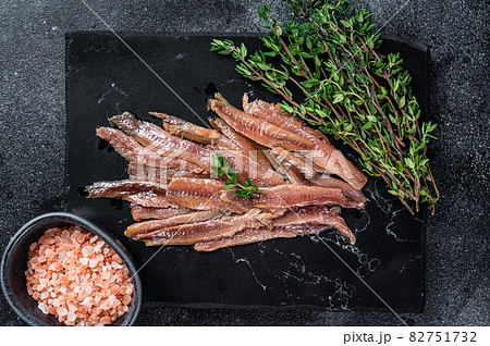 Anchovies fish fillet in Olive Oil. Black background. Top view Anchovies fish fillet in Olive Oil. Black background. Top view 82751732