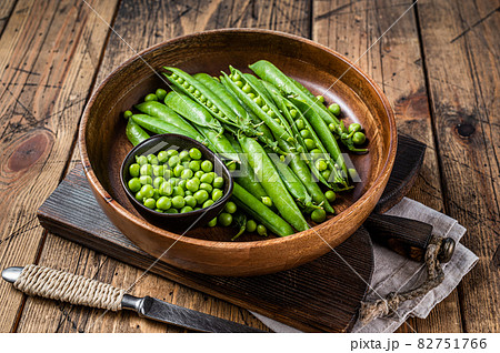 Unpeeled young green pea pods in a wooden plate. wooden background. Top view Unpeeled young green pea pods in a wooden plate. wooden background. Top view 82751766
