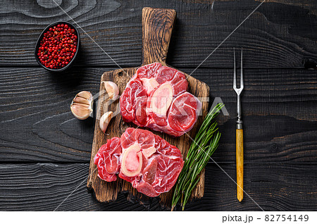 Raw meat osso buco veal shank steak , making italian ossobuco. Black Wooden background. Top view Raw meat osso buco veal shank steak , making italian ossobuco. Black Wooden background. Top view 82754149