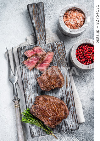 Roasted fillet mignon or tenderloin beef steak on wooden cutting board. White background. Top view 82754151