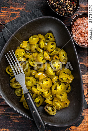 Preserved Jalapenos, pickled and sliced in plate . Dark Wooden background. Top view 82754176