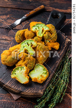Crumbed broccoli steaks on a wooden board. Dark wooden background. Top view Crumbed broccoli steaks on a wooden board. Dark wooden background. Top view 82754281