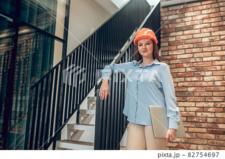 Smiling woman in safety helmet with laptop 82754697