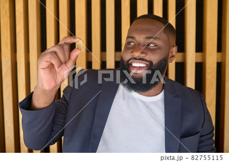A bearded dark-skinned man holding a bitcoin A bearded dark-skinned man holding a bitcoin 82755115