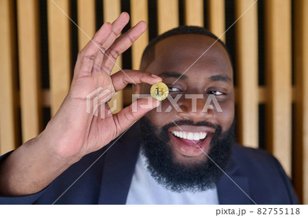 A bearded dark-skinned man holding a bitcoin A bearded dark-skinned man holding a bitcoin 82755118
