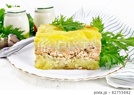 Casserole with potatoes and fish in plate on wooden board Casserole with potatoes and fish in plate on wooden board 82755682