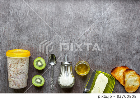 Oatmeal with kiwi, toast with butter and honey on a wooden table 82760808