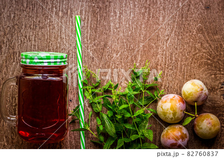 Glass with fresh Plum Juice and green mint on vintage wooden background Glass with fresh Plum Juice and green mint on vintage wooden background 82760837
