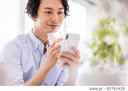 笑顔でスマホの画面を見る若い男性 82761420