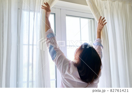 Close-up of woman's hand opening and closing light translucent curtains 82761421