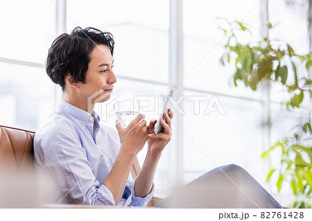 笑顔でスマホの画面を見る若い男性 82761428