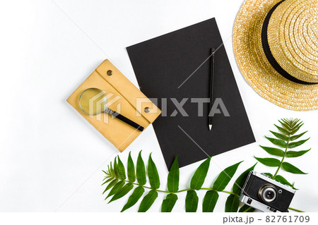 Straw hat with green leaves and old camera on white background, Summer background. Top view Straw hat with green leaves and old camera on white background, Summer background. Top view 82761709
