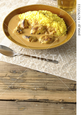 ランチョンマットに置かれたお肉ゴロゴロタンドリーチキンバターカレーとお茶 82763511