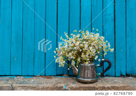 Summer bouquet of white daisies, in an iron vase, on a wooden background 82768790