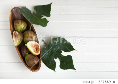 Figs in a wooden plate with leaves 82768910