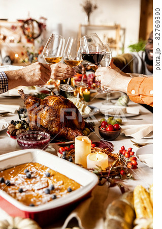 Close-up happy multiethnic big family celebrate Thanksgiving day, sitting at table with roasted turkey and holiday traditional food, dishes. 82769390