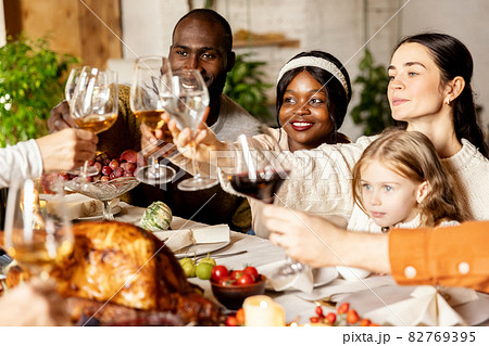 Happy family celebrate Thanksgiving day, sitting at table with roasted turkey and holiday traditional food, dishes. Drinking wine 82769395