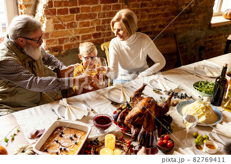 Happy grandfather, grandmother and grandson celebrate Thanksgiving day at home, indoors. 82769411
