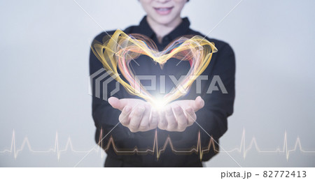 白い明るい背景と日本人女性の手とハートとヘルスケアイメージのテクノロジーのホログラムのCGグラフィッ 82772413