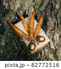A gift wrapped in craft paper and decorated with dried fern leaves and glass acorns. 82772516