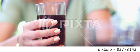 Woman hand holds glass beaker with brown liquid Woman hand holds glass beaker with brown liquid 82773142