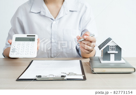 Agents working in real estate investment There a house model Hold a pen and a calculator and home lease contract And home insurance According to the insurance contract Home purchase approved Buy for 82773154