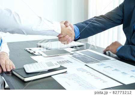 Shaking hand two business leaders talk about charts, financial graphs showing results are analyzing and calculating planning strategies, business success building processes 82773212