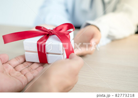 A hand holding a gift box Glad to be the giver of surprise with excitement, joy on the holidays, Christmas, birthdays, or Valentine's Day concept 82773218