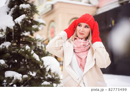 Snowfall woman city christmas outside, city portrait in snowfall, young model posing in festive look 82773499
