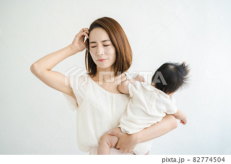 赤ちゃんを抱えて、疲れた表情をするお母さん 82774504