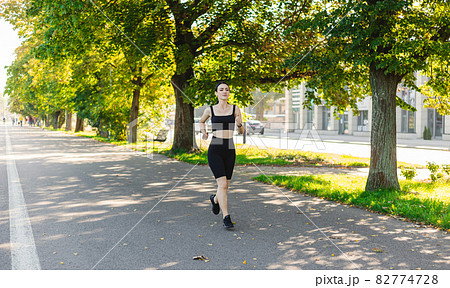 Athletic young happy woman runing in the park jogging in the morning for lifestyle health. Outdoor workout. Sport and healthy active lifestyle concept. 82774728