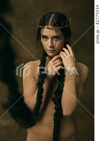 Art portrait of beautiful woman in crown with long black braids tenderly looking at camera isolated over vintage background. Antique style Art portrait of beautiful woman in crown with long black braids tenderly looking at camera isolated over vintage background. Antique style 82775034