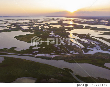 Aerial drone view of a swamp at amazing bright sunset. Aspalt Road through the Lakes and Marsh Aerial drone view of a swamp at amazing bright sunset. Aspalt Road through the Lakes and Marsh 82775135