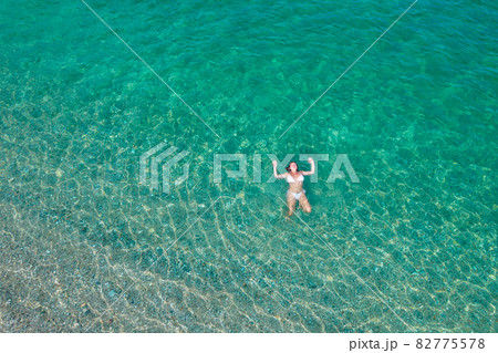 Young woman in a swimsuit lying on sea water on the beach. View from above. Top, drone view 82775578
