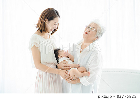 赤ちゃんを抱っこするシニア女性と見守る女性たち 82775825