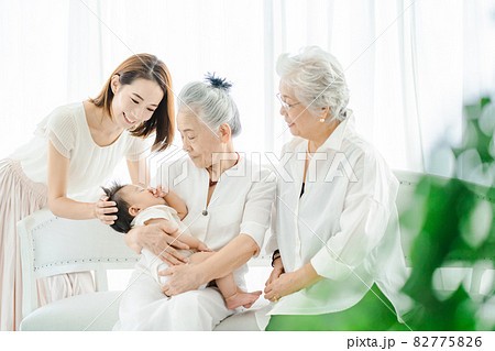 赤ちゃんを抱っこするシニア女性と見守る女性たち 82775826