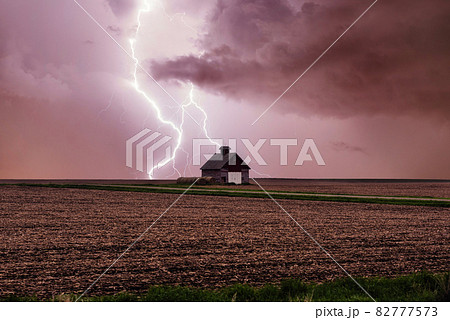 One rural barn, house in the middle in field on stormy sky with lightning strike background. One rural barn, house in the middle in field on stormy sky with lightning strike background. 82777573