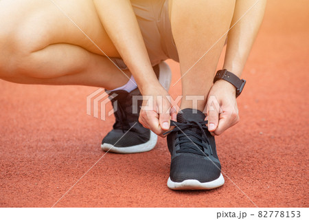 Close up of runner woman tying shoelaces. Conceptual of woman getting ready for jogging in the running track. Close up of runner woman tying shoelaces. Conceptual of woman getting ready for jogging in the running track. 82778153