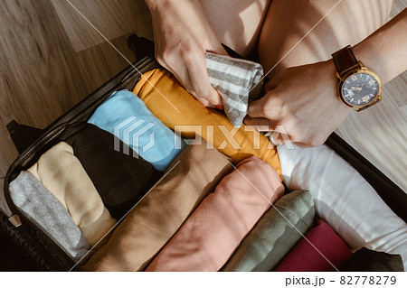 Close up of tourist woman open suitcase roll and pack colorful cloths for travelling. Conceptual of travel and holiday background. 82778279