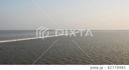 The tidal bore on the estuary of the Qiantang River. Northern bank of the Qiantang River near Hangzhou in Zhejiang Province, China. The southern bank is visible in the distance. The tidal bore on the estuary of the Qiantang River. Northern bank of the Qiantang River near Hangzhou in Zhejiang Province, China. The southern bank is visible in the distance. 82779985