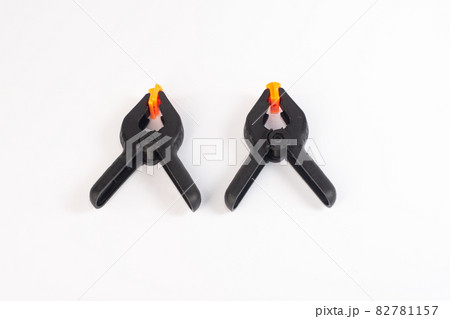 Two black construction clothespins on a white background. close-up Two black construction clothespins on a white background. close-up 82781157