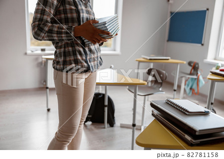 Female teacher holding many books in classroom 82781158