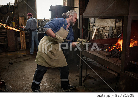 Craftsman working furnace in blacksmiths shop Craftsman working furnace in blacksmiths shop 82781909