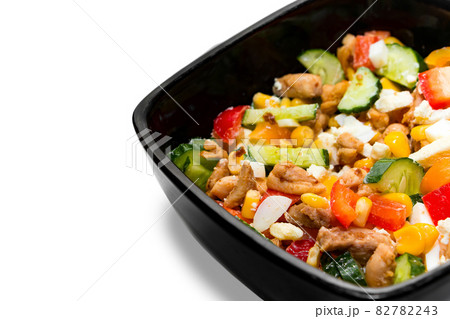Tasty vegetable salad with chicken in a black plate Isolated on white background. Black bowl with bright vegetable salad and chicken close-up isolated on a white background 82782243